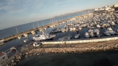 Video, nefes kesici bir liman görüntüsüyle açılıyor. Kristal berrak su, küçük balıkçı teknelerinden lüks yatlara kadar çeşitli teknelere ev sahipliği yapıyor. Uzakta, yalnız bir jet ski.