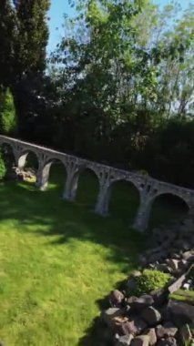 Kendinizi canlı çiçeklerle, yemyeşil çiçeklerle ve büyüleyici minyatür binalarla dolu çarpıcı bir bahçenin sükunetine daldırın. Videomuz sizi bu resimde huzurlu bir yolculuğa çıkarıyor.