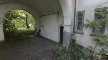 Bu unutulmaz video sizi terk edilmiş bir tımarhanenin harap olmuş kalıntıları arasında tüyler ürpertici bir yolculuğa çıkarıyor. Ürkütücü avluya adım attığınızda, dağılan duvarlar ve büyüyen yapraklar