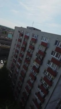 Video yukarıdan bir şehrin görüntüsüyle başlıyor. Kamera daha sonra bir konut binasına zumluyor. Kamera binanın etrafında döner, farklı daireleri ve balkonları gösterir. Kamera.