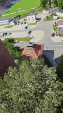 Bu, restore edilmiş antik bir gözetleme kulesinin inanılmaz bir hava görüntüsü. Gözetleme kulesi kırmızı tuğladan yapılmıştır ve konik bir çatısı vardır. Etrafı ağaçlar ve parklarla çevrili. Arka planda, meşgul birini görebilirsiniz.