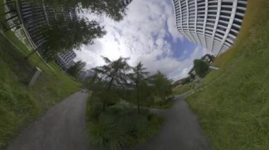 Bu 360 derecelik video peyzajlı bir ofis parkının panoramik görüntüsünü sağlıyor. Parkta birçok yüksek ofis binasının yanı sıra çeşitli ağaçlar, bitkiler ve çiçekler yer alıyor. Bir yürüyüş var.
