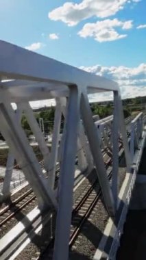 Video yukarıdan bir köprü görüntüsüyle başlıyor. Köprü, beyaz boyalı çelik bir yapı. Bu bir kiriş köprüsü, yani bir dizi üçgenden oluşuyor. Köprü