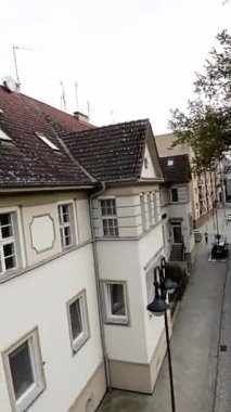 Bu video yerleşim alanındaki sessiz bir sokağı gösteriyor. Sokak ağaçlarla dolu ve yolun kenarına park edilmiş birkaç araba var. Video yüksek bir açıdan çekiliyor ve izleyici...