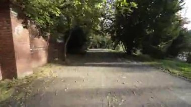 Video, parktan uçan bir İHA 'nın birinci şahıs görüntüsü. İnsansız hava aracı ağaçlarla kaplı dar yollarda uçuyor ve birkaç park sırasını geçiyor. Video sonbaharda çekiliyor, yapraklar gibi.