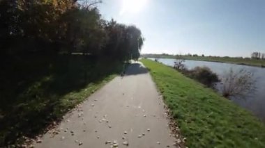 Bu FPV İlk Kişi Görünümü uçuşu sizi güzel bir nehir kıyısına götürüyor. Uçuş bir parkta başlıyor. Duvarda renkli bir duvar resmi ve gür ağaçlar göreceksiniz. Sonra birlikte uçacaksınız.