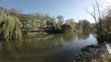 Video, sonbaharda nehrin üzerinde uçan bir İHA 'nın birinci şahıs görüntüsüyle başlıyor. İnsansız hava aracı nehir boyunca uçuyor, köprünün altından ve ağaçların arasından geçiyor. Su koyu yeşil bir renktir.