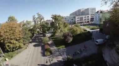 Video, sonbaharda bir parkın kuş bakışı görüntüsüyle açılıyor. Ağaçlar tam yeşillik ve renkler canlı. Parkta bir patika esiyor ve birkaç kişi yürüyor ve bisiklete biniyor. İçeri