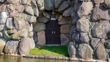 Küçük antika bir kapısı olan taş bir duvar antika ve konforlu bir ortam yaratır..