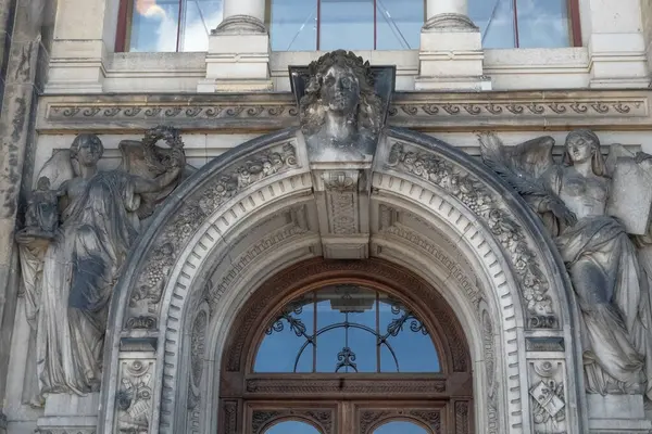 Tarihi bir binanın ön cephesinde maskarası ve heykel figürleriyle dekore edilmiş mimari portal..