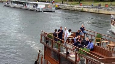 İnsanlar Spree Nehri 'nde yüzen bir kafede dinleniyor.