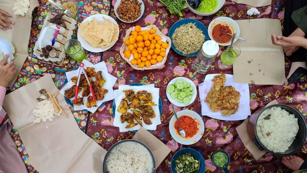 top view with hand Various food buffet seved an floor dining style with bokeh background. Often in ramadan month and islam eid al fitr and al adha celebration