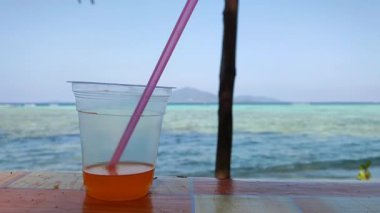 Karimun Jawa sahilinin kenarında sıcak güneş ve yanında bir bardak portakal suyu.