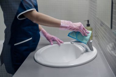 Close up of chambermaid hands cleaning tap in bathroom. High quality photo clipart