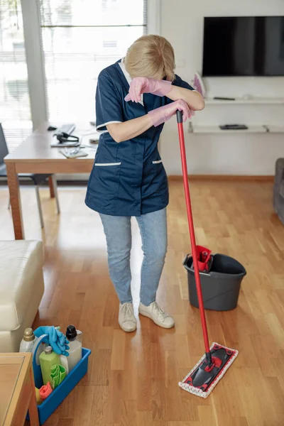 Trött Hushållerska Uniform Tvättgolv Och Böja Sig Över Mopp Vardagsrummet — Stockfoto