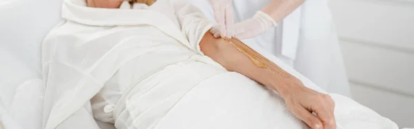 Specialist doing sugaring depilation removing unwanted hair to woman patient, spa and wellness