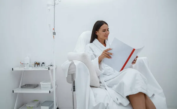 Kobieta Białym Szlafroku Czyta Magazyn Podczas Siedzenia Luksusowym Centrum Wellness — Zdjęcie stockowe
