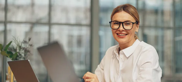 stock image Smiling businesswoman working on laptop while sitting in modern coworking. High quality photo