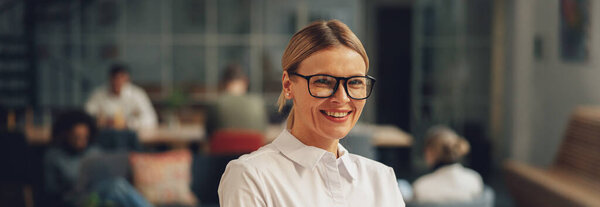 Smiling businesswoman showing thumb up while standing in office. High quality photo