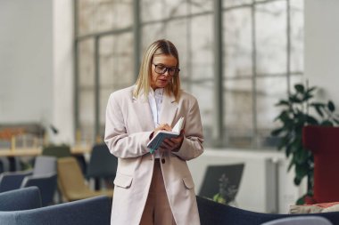 Gözlüklü kadın muhasebeci rahat ofiste çalışırken not alıyor. Yüksek kalite fotoğraf