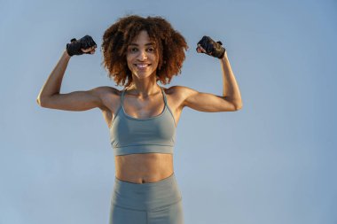 Spor kıyafetli kadın stüdyo arka planında duran kaslarını gösteriyor. Çalışma sonuçları