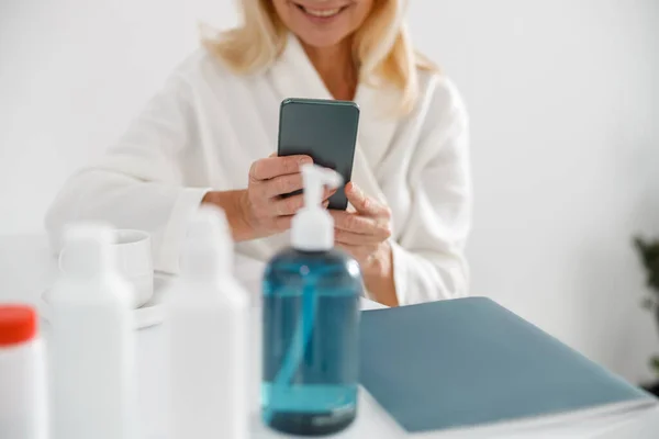 Nerozpoznatelná Blondýna Starší Žena Sedí Kosmetickém Centru Používá Mobilní Telefon — Stock fotografie