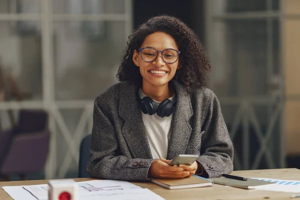 現代の同僚の携帯電話で座っている間 女性のフリーランサーはカメラで笑顔 高品質の写真 — ストック写真