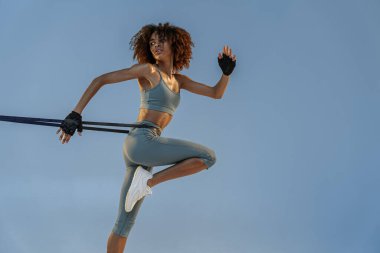 Woman performs exercises with expander on studio background. Strength and motivation