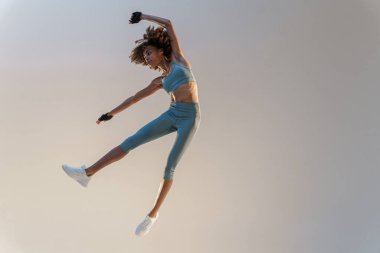 Athletic active woman jumping on studio background. Dynamic movement