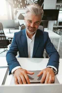 Modern bir iş birliğinde otururken dizüstü bilgisayarla çalışan meşgul bir iş adamı. Yüksek kalite fotoğraf