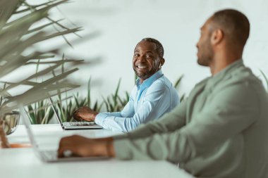 Bilgisayarda çalışan Afrikalı iş adamı meslektaşlarının geçmişini araştırıyor. Yüksek kalite fotoğraf