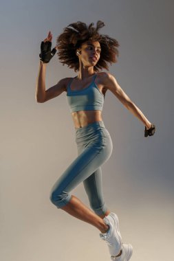Stüdyonun arka planında atlayan atletik aktif kadın. Dinamik hareket