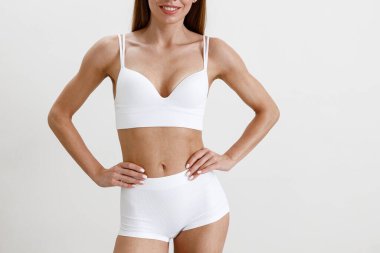 Stüdyo arka planında beyaz iç çamaşırı giyen ince ve güzel bir kadın vücudu. Yüksek kalite fotoğraf