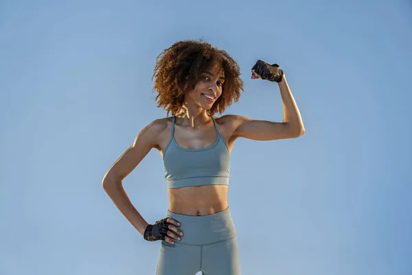 穿着运动服的女人站在演播室背景上炫耀她的肌肉 工作成果 — 图库照片