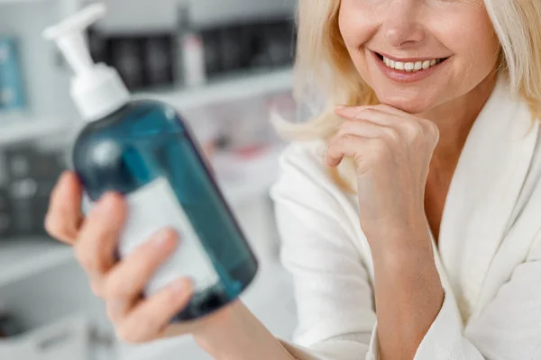 美丽的笑容满面的白种人年长的金发女人坐在健康中心 手里拿着一瓶 — 图库照片