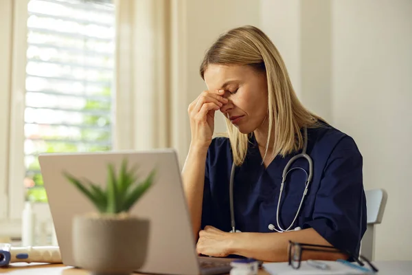 stock image Tired female healthcare worker using laptop while working at doctors office