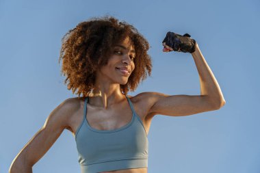 Spor kıyafetli kadın stüdyo arka planında duran kaslarını gösteriyor. Çalışma sonuçları