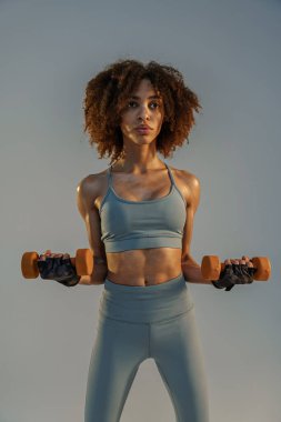 Stüdyo arka planında dambıllarla egzersiz yapan bir kadın. Spor ve sağlıklı yaşam tarzı