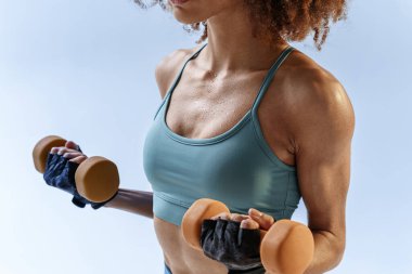 Stüdyo arka planında dambıllarla egzersiz yapan bir kadın. Spor ve sağlıklı yaşam tarzı