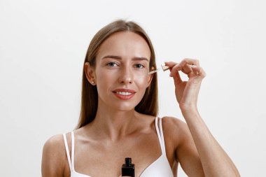 Kadın elinde kozmetik içeren bir şişe tutuyor. Nemlendirici serum, yağ, yüz özü. Yüksek kalite fotoğraf