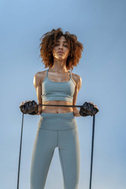 Spor giyim sektöründe güçlü bir kadın stüdyo arka planında direnç bandıyla fitness egzersizleri yapıyor.