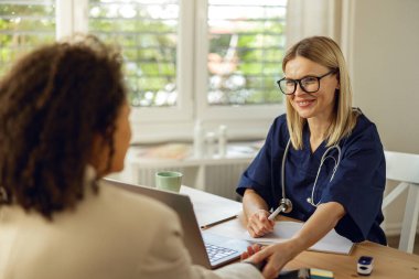 Doktor terapist, modern bir klinikte bir kadının muayenehanesinde önleyici bir inceleme yapıyor.