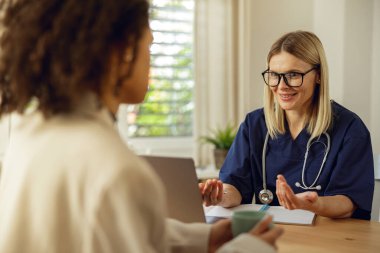 Kadın doktor randevusu sırasında hastaların tıbbi bakım formlarını doldurur.