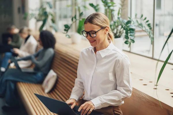 女经理坐在靠窗的地方 在现代同事的笔记本电脑上工作 高质量的照片 — 图库照片