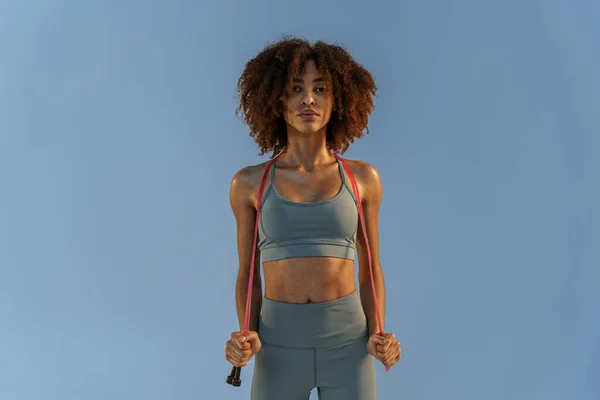 Portrait of smiling athletic woman with jump rope on studio background. High quality photo