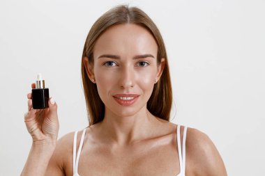 Kadın elinde kozmetik içeren bir şişe tutuyor. Nemlendirici serum, yağ, yüz özü. Yüksek kalite fotoğraf