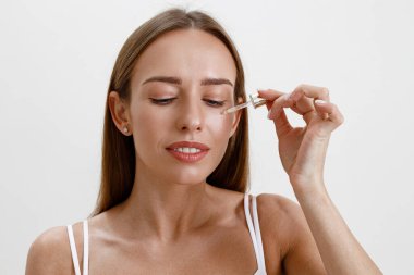 Kadın elinde kozmetik içeren bir şişe tutuyor. Nemlendirici serum, yağ, yüz özü. Yüksek kalite fotoğraf