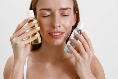 Stüdyo arka planında cilt bakım ürünleri tutan gülümseyen kadın. Yüksek kalite fotoğraf