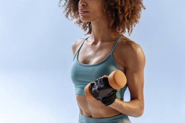 Stüdyo arka planında dambılla egzersiz yapan bir kadın. Spor ve sağlıklı yaşam tarzı
