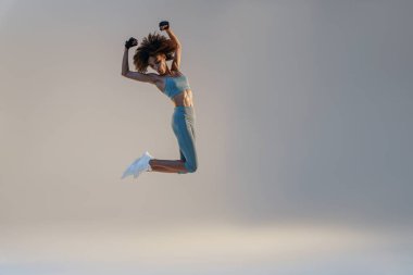Athletic active woman jumping on studio background. Dynamic movement